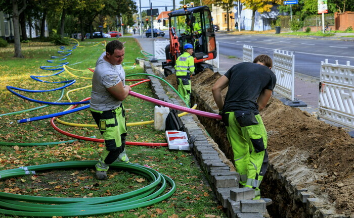 Arbeiter verlegen an einer Straße Leerrohre für den Glasfaserausbau